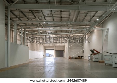 Spacious expansive warehouse interior with high ceilings, large open floor area. Concept of industrial warehouse, logistics, warehouse storage solutions, or commercial space potential. Royalty-Free Stock Photo #2442607489