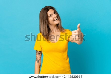 Young slovak woman isolated on blue background with thumbs up because something good has happened