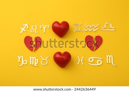 Zodiac compatibility. Signs with red whole and broken hearts on yellow background, flat lay Royalty-Free Stock Photo #2442636449