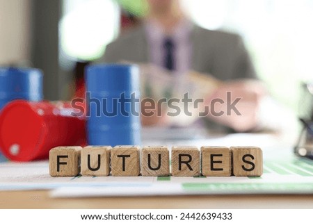 Word futures collected from wooden cubes with oil barrels on office table and blurred business person in background. Concept of futures and oil price and trading.