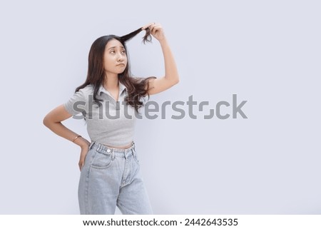 Asian girl feels sad and anxious seeing the condition of her hair, isolated on white background