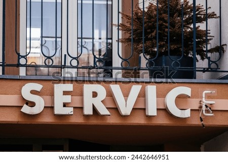 A sign with the word Service displayed on the side of a building in a commercial area - with last letter only with Neon sign seen