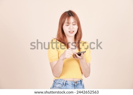 Upset stylish caucasian girl talking on phone, standing with smartphone against yellow studio background. Young Asian woman. stressed and sad. girl emotions. Using mobile phone.
