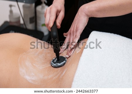 Professional conducts lumbar rehabilitation using electrotherapy. Royalty-Free Stock Photo #2442663377