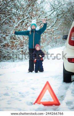 woman with a child on the winter road. emergency sign