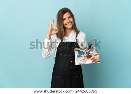 Young artist Slovak woman isolated on blue background showing ok sign with fingers