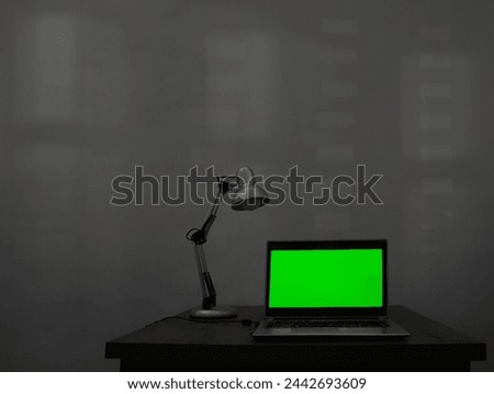 mock up. Laptop with blank green screen, and office on wooden desk. Blank computer monitor on wood table with lamp light. isolated on white wall background. mockup. night evening scene. 