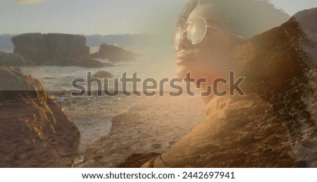 Image of african american woman in sunglasses over sunny landscape. happy holidays and free time, digitally generated image.