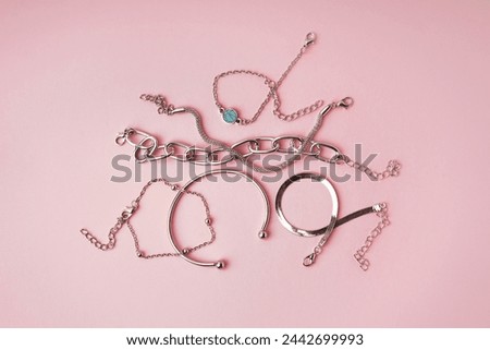 Many different stylish bracelets on pink background