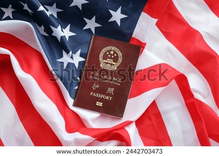 Red passport of People Republic of China on United States flag. PRC chinese passport on bright background close up Royalty-Free Stock Photo #2442703473