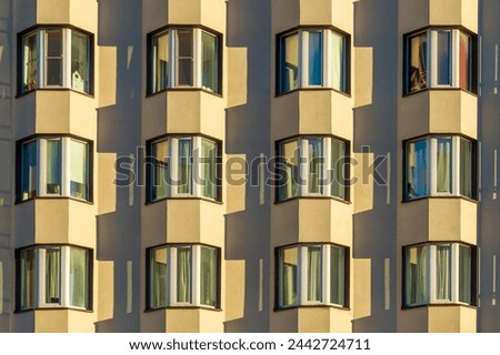 A tall building with many bay windows. The building appears to be a residential apartment building, with many windows on each floor. The sunlight is shining through the windows Royalty-Free Stock Photo #2442724711