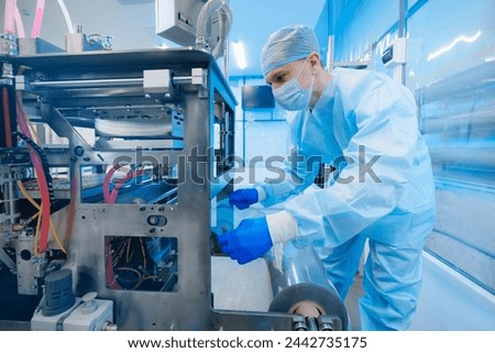 Worker control production line automatic machine for manufacture of medical plastic form for surgical kit on medicine factory. Royalty-Free Stock Photo #2442735175