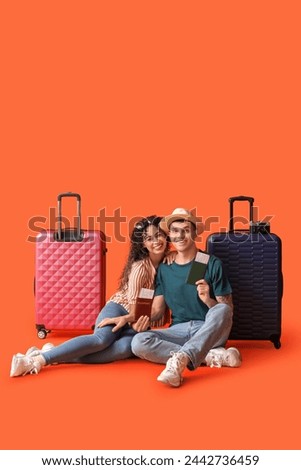 Couple of tourists with suitcases and passports on orange background