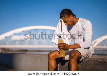 Portrait of tired young african-american man who wipes the sweat from his face after jogging.