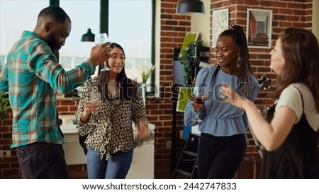 Group of friends dancing at apartment party, having fun together, moving their feet on rhythm. BIPOC people doing energetic dance moves on upbeat songs in brick wall living room Royalty-Free Stock Photo #2442747833