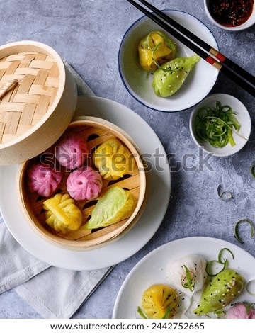 Top down view of colourful handmade dim sum served in a bamboo steamer.