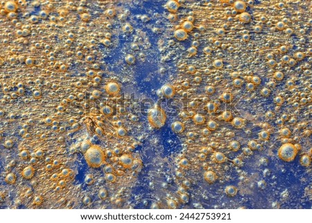Rust stains and air bubbles on the surface of polluted water from industrial plants and urban areas.