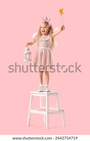 Cute little fairy with lantern on stool against pink background