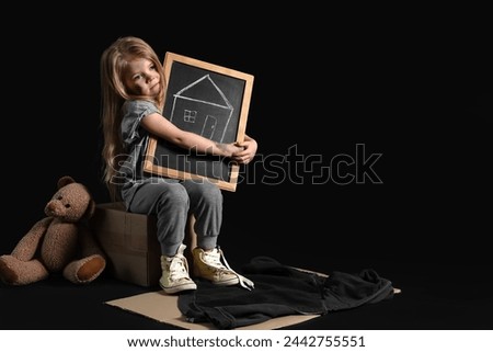 Homeless little girl with picture of house and teddy bear on dark background