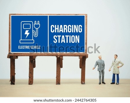 Mini toy of action figure at table with blurred background. Toy photography concept. Electric Vehicle Charging Station sign conceptual design.