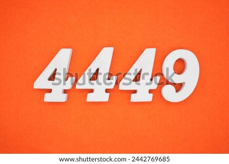 Orange felt is the background. The numbers 4449 are made from white painted wood. Royalty-Free Stock Photo #2442769685