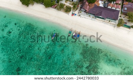 Aerial view of traditional Thai long tail boats at a beach at Koh Phi Phi island, Krabi, Thailand. Tropical paradise white sand beach with no people, turquoise waters of Andaman sea. 