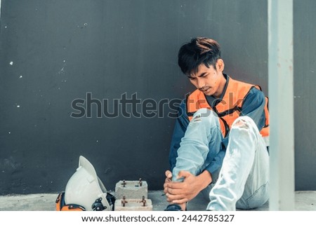 Asian HVAC engineer suffered serious leg injury on the job. Urgent first aid and assistance from coworkers is essential. Expressions of pain on face convey physical and emotional response. Royalty-Free Stock Photo #2442785327