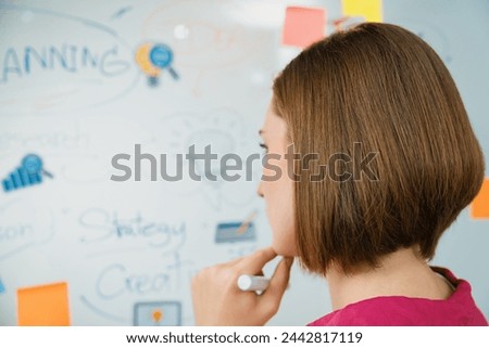 Portrait of young beautiful caucasian businesswoman thinking creative marketing strategy idea in front of whiteboard with mind map and colorful sticky notes. Arm chin. Closeup. Immaculate. Royalty-Free Stock Photo #2442817119