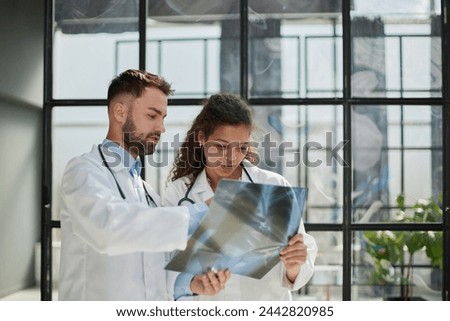 Young serious competent male doctor looking at X-ray at doctor's office