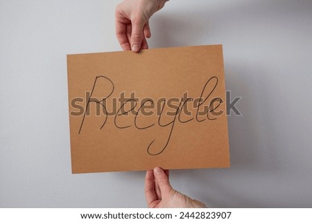 Two hands holding banner with written sign recycle