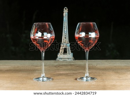 Two glasses of pink wine on a wooden table against the black background with the eiffel tower