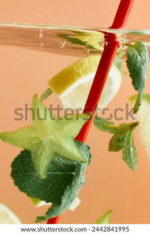 Slices of lemon and starfruit with mint leaves submerged in water with red straw. Refreshing lemonade. Texture of cooling sweet summer's drink. Concept of food and drinks, nutrition, freshness
