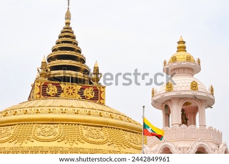 The golden pagoda and Myanmar flag in the Buddhist temple of Mandalay