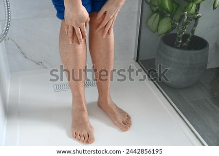 Hairy female legs in bathroom interior.