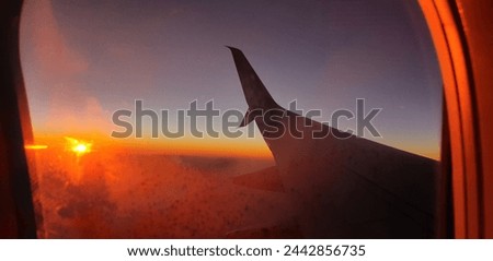 This is a picture of a sunset out of an airplane window, taken high above the clouds. The atmosphere is clearly visible in this photo, as well as the colours of the night sky.