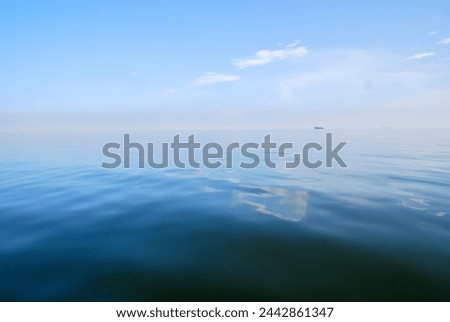 Ocean water and sky touching background with a ship far away on the horizon.