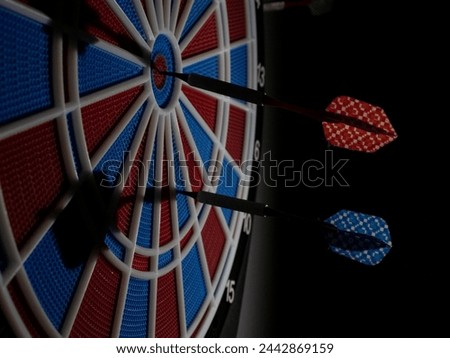 The picture shows the play of light and shadow on a dart board and darts