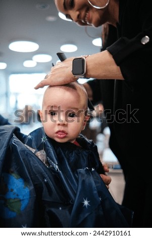 Woman hairdresser cutting baby's hair with scissors in a hairdressing salon