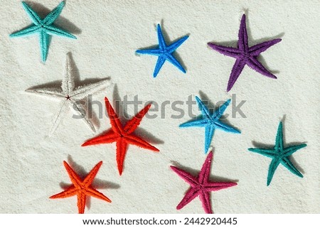 Colored starfish on white fine sand. Summer background, free space for your decoration, flat lay.