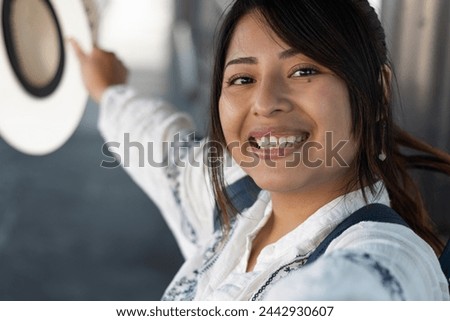 Horizontal selfie photo of a smiling female tourist wearing traditional Mexican clothing and a hat while traveling alone in her 20s; laughing while she looks at the camera and enjoys her vacation
