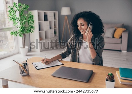 Photo of happy smiling lady broker dressed shirt talking modern gadget writing documents indoors workshop workplace workstation
