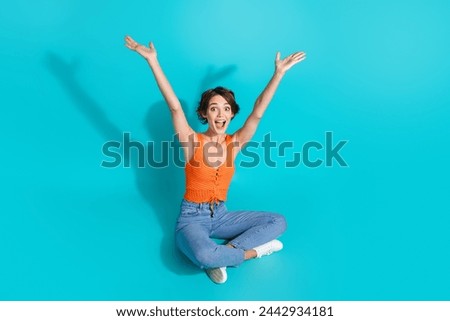 Full length photo of nice woman wear orange singlet sitting raising arms up presenting black friday isolated on turquoise color background