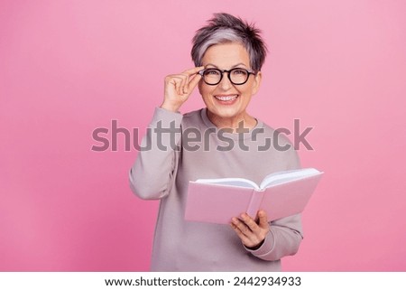 Photo of cheerful adorable retired woman wear stylish clothes reading novel poetry book textbook isolated on pink color background