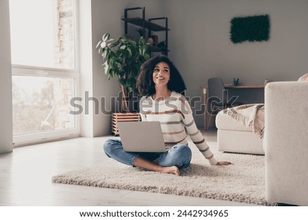 Photo portrait of attractive young woman sit floor look empty space netbook dressed casual clothes cozy day light home interior living room