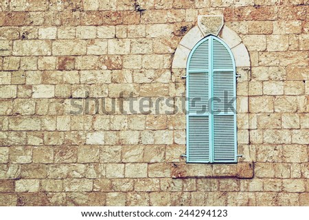 old house's wall from jerusalem stone and old blue iron shutters. retro filtered image 