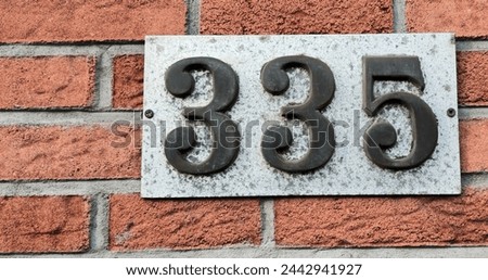 Number plate. Number 335 against a red brick wall background. Concept from a room and a wall. High resolution 150 megapixels Royalty-Free Stock Photo #2442941927