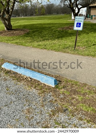 Reserved Parking spot at a local town park including a reserved parking sign as well as a blue painting curb stopper.