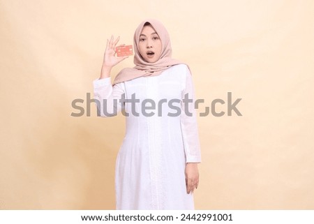asian muslim woman in hijab shocked holding debit credit card in hand and hands down. Lifestyle, business and finance concept