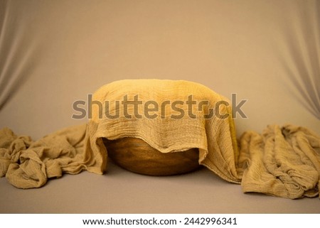 Newborn photography background decorated with a wooden bowl covered with brown swaddling cloth