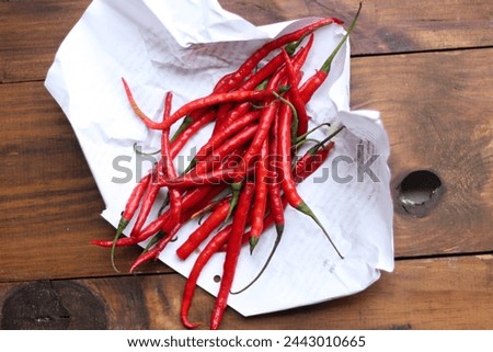 Top View Red Chili on Wooden background covered white paper.  Royalty-Free Stock Photo #2443010665